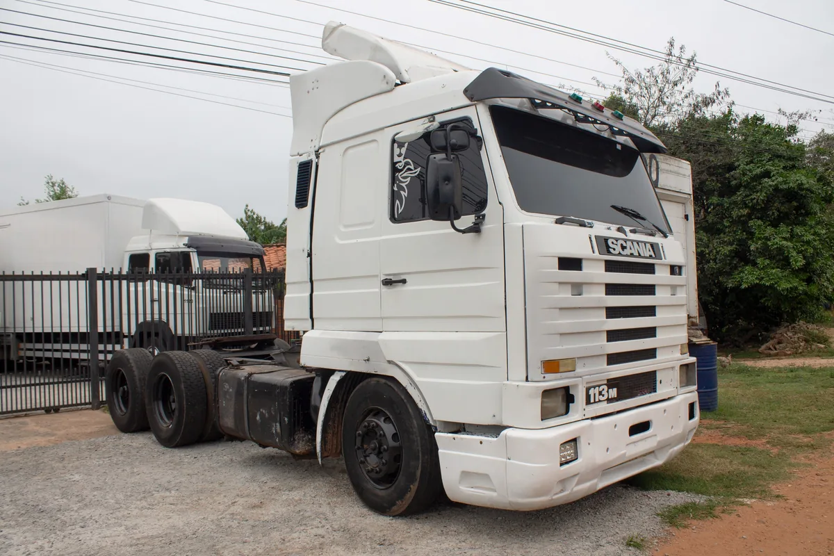 Tractocamión Scania 113 M blanco de tres ejes, de frente en el patio